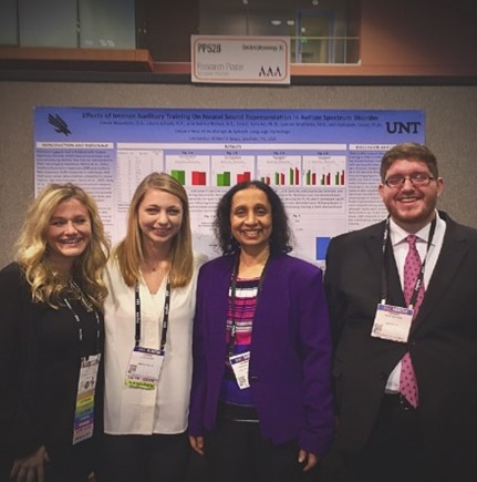 Dr. Gopal and two of her research group standing in front of a poster at an academic conference