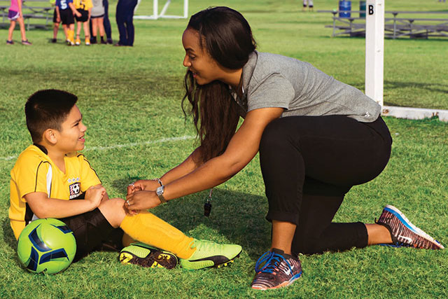 Woman working with a child on a soccer field