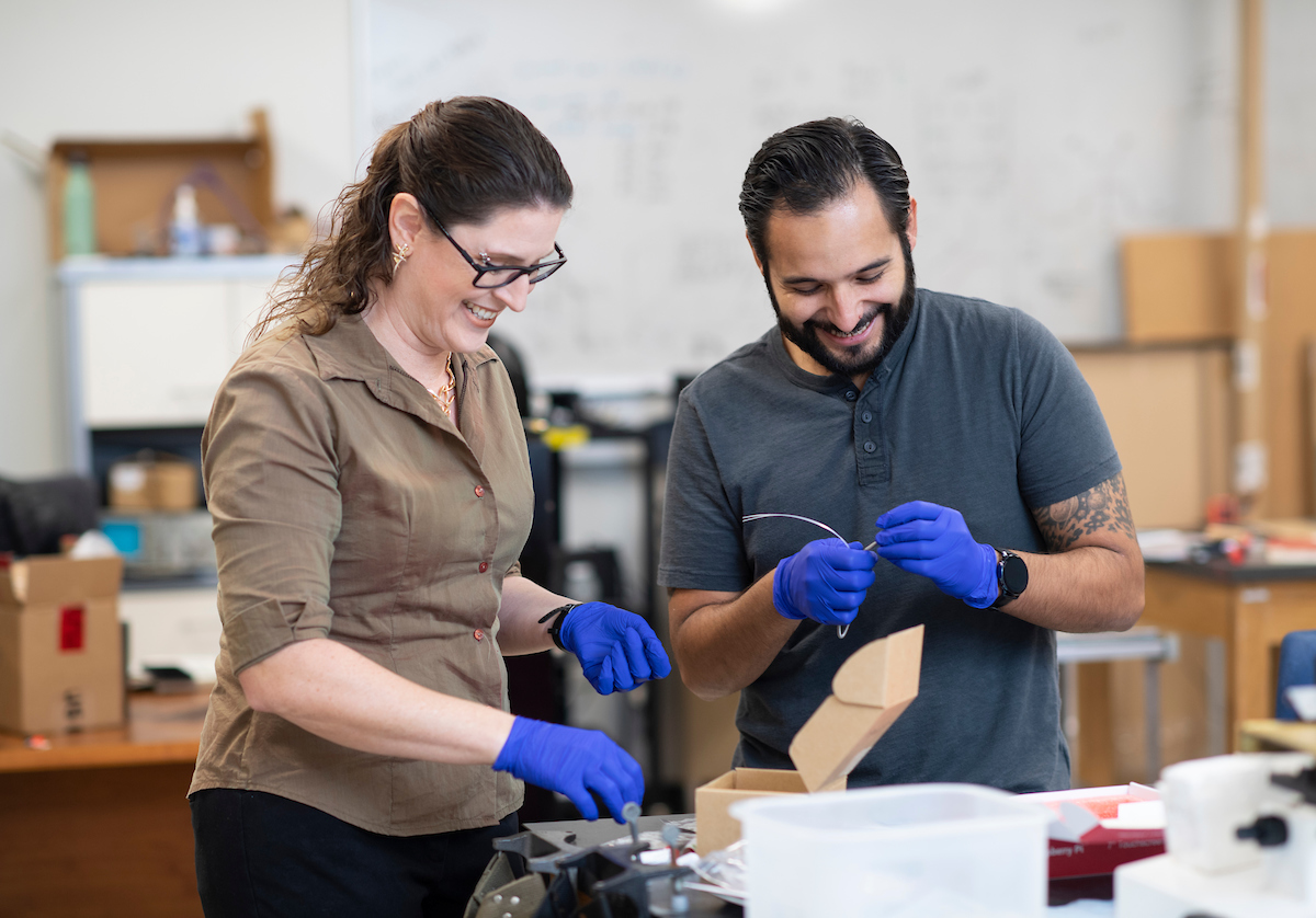 Faculty and a graduate student researching in a lab