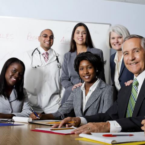 Health services employees standing and sitting together in a conference room