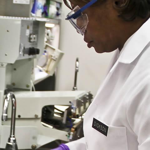 Researcher in lab coat working at a sink