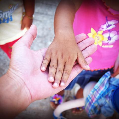 Child's hand on top of adult's hand