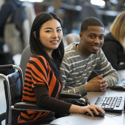 Two students working on a laptop