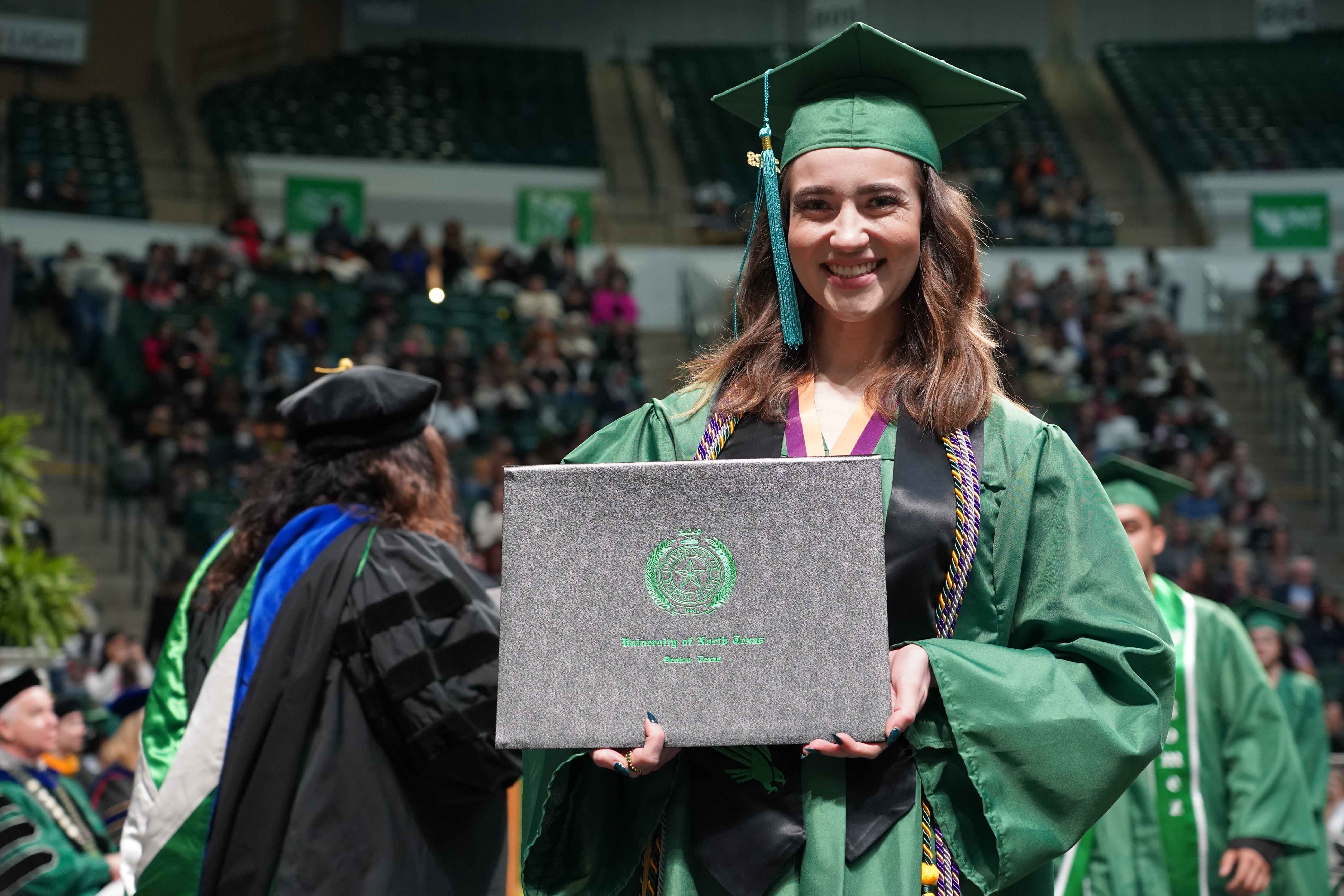 Girl walking across stage at commencement smiling