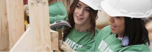 Two girls volunteering by building a house