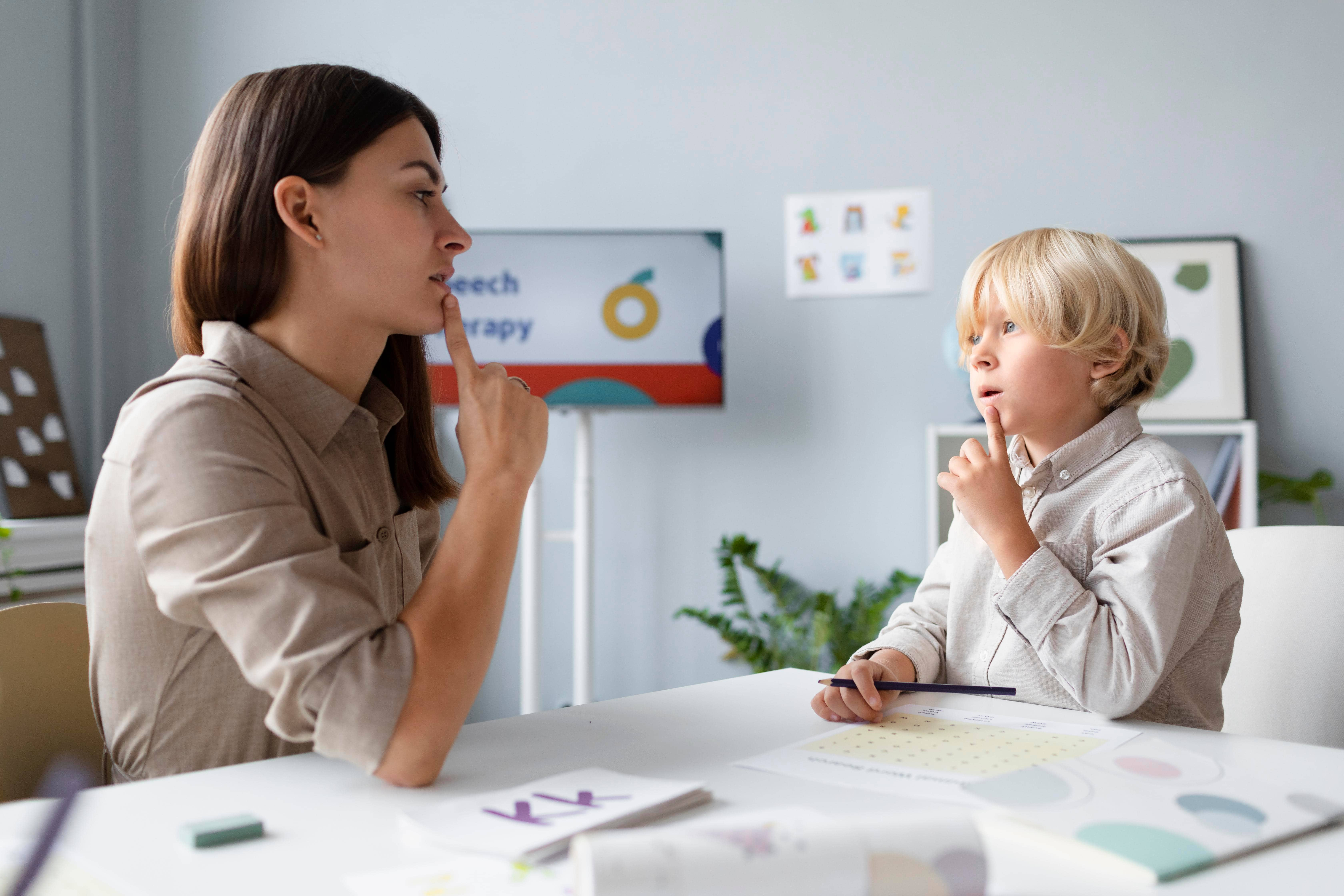 Female speech pathologist helping a young boy mouth words